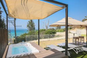 恩纳Hermit Hills Okinawa  -SEVEN Hotels and Resorts-的一个带桌子和遮阳伞的庭院和一个游泳池
