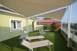 代森扎诺-德尔加达阿斯托里亚酒店的露台设有遮阳篷,阳台上配有桌椅
