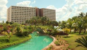 奥林匹亚Hot Beach Resort的一座带游泳池、棕榈树和建筑的度假村