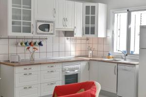 莫甘Casa Apolo的白色的厨房,配有白色的橱柜和红色的椅子