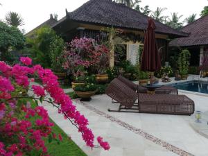 甘地达萨凤梨别墅的庭院设有两把椅子和一把遮阳伞,鲜花盛开