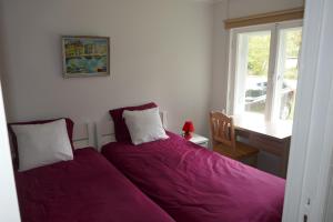凯尔德拉Kärdla Holiday House的一间卧室配有一张带紫色床单的床和窗户。
