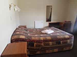 福克斯冰川库克山景汽车旅馆的一间卧室配有一张带毯子和桌子的床