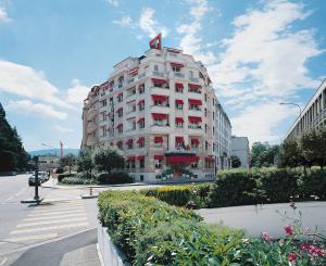 日内瓦伊甸酒店的街道上一座白色的大建筑,设有红色窗户