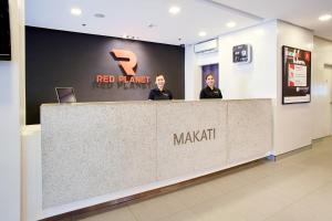 马尼拉Red Planet Makati Avenue Manila的两个女人站在一个红色羽毛药房的柜台上