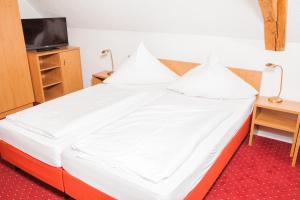 图特林根泽尔滕巴彻霍夫酒店的一张带白色床单和枕头的床