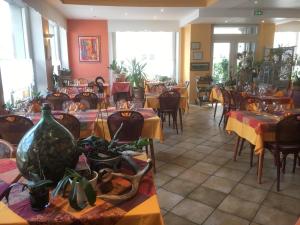 奥尔贝布鲁耶尔酒店的一间设有桌椅的餐厅,种植了植物