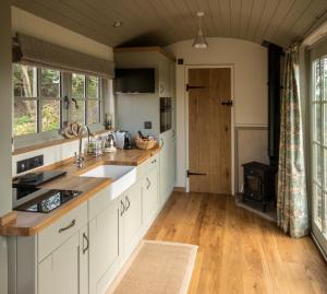 BransgoreLuxury Shepherds Hut的厨房铺有木地板,配有白色橱柜。