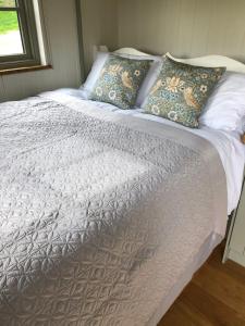 BransgoreLuxury Shepherds Hut的一张带白色床单和枕头的床