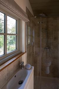 BransgoreLuxury Shepherds Hut的带淋浴和盥洗盆的浴室以及窗户。