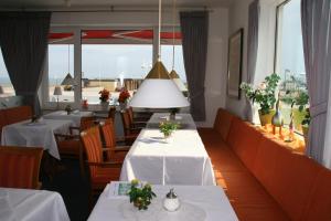 黑尔戈兰岛汉斯特酒店的餐厅设有白色的桌椅和窗户。