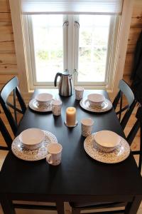 ÅlvundeidCamp Dronningkrona的一张黑桌,上面有盘子、杯子和蜡烛