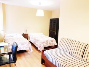 马德里Hostal Puerta Bonita Vista Alegre的一间带两张床和一张沙发的客厅