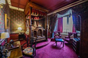 切斯特勒斯特里特拉姆利城堡酒店的一间卧室配有一张天蓬床和紫色地毯