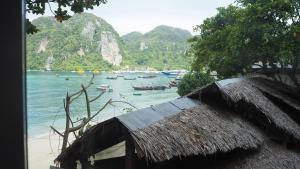 皮皮岛Chaokoh Phi Phi Hostel的海滩上的小屋,船上有船只