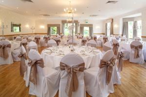 邓弗姆林加沃克之家酒店的宴会厅配有白色的桌椅和弓形