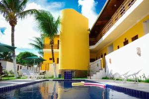 康德Pousada Brisa Marine的一座棕榈树的黄色建筑和游泳池