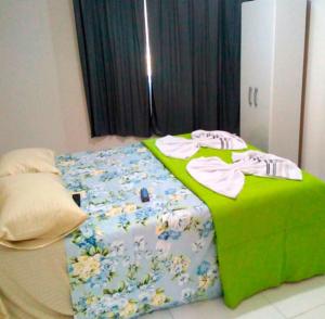 迈里波朗Pousada Oluap的一张位于房间的床,上面有绿毯和衣服
