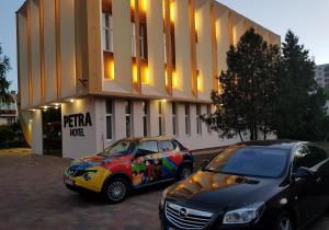 尼赖吉哈佐Petra Hotel的两辆汽车停在大楼前的停车场