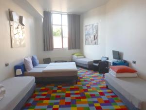 布鲁塞尔凡其酒店的客厅配有三张床和色彩缤纷的地毯。