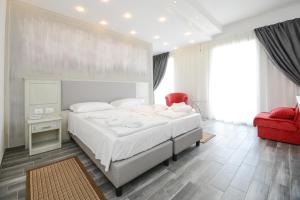 莫尼加Front Lake Hotel Villa Paradiso Suite的一间卧室配有一张大床和一张红色椅子