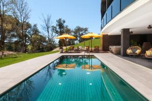 卡尔德斯德马拉维亚LAVIDA Hotel at Camiral Golf & Wellness的一座带椅子和遮阳伞的游泳池位于一座建筑旁边