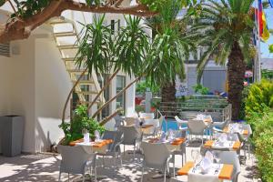 罗希姆诺奥林匹克一号酒店的一间设有桌椅的餐厅,种植了棕榈树