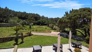 辛特拉Quinta do Cabo Guesthouse的公园配有桌椅,公园绿树成荫