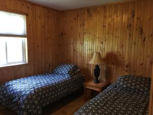 皮克顿Merland Park Cottages and Motel的木墙客房的两张床