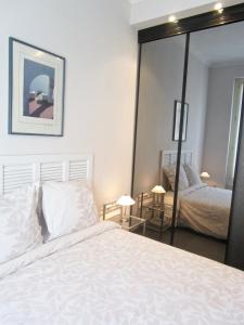 尼斯公寓的卧室配有白色的床和大镜子
