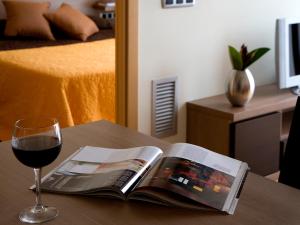 卡斯特尔德费尔斯SG科斯塔巴塞罗那公寓式酒店的一本书和一张桌子上的一杯葡萄酒
