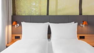 慕尼黑假日酒店慕尼黑 - 洛伊希滕贝格环路的卧室内的两张床和白色枕头