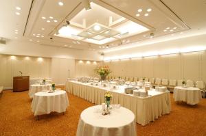 长野长野日航城市酒店的宴会厅配有白色的桌椅