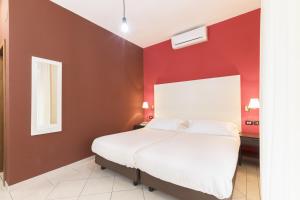巴里Hotel La Baia的卧室设有红色的墙壁和白色的床。