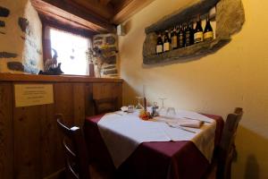 尚波吕克L' Aroula Rooms & Restaurant的餐厅的一张桌子,墙上装有葡萄酒瓶