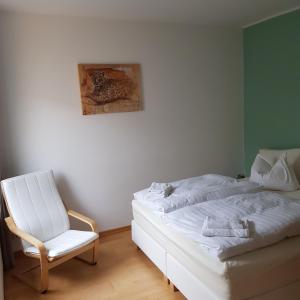 瓦尔内明德Twee Linden Warnemünde Zentrum的卧室配有白色的床和椅子
