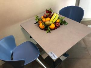那不勒斯那不勒斯肯姆艾拉酒店的桌上一碗水果和两把蓝色椅子