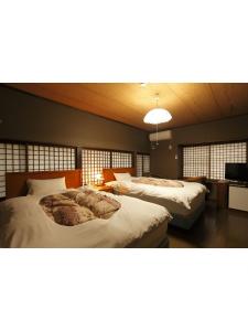 会津若松田事日式旅馆的一间卧室配有两张床和电视。