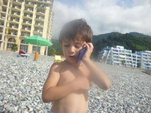 Kvariat'iАпартаменты свидом наморе Гонио的海滩上一个用手机说话的男孩