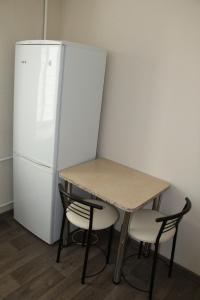 哈尔科夫Современная 1-комнатная квартира的冰箱旁的一张桌子和两把椅子