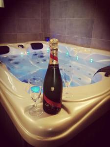 AvelinAutrement Spa的浴缸内的一瓶香槟和两杯葡萄酒
