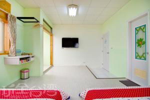 马公澎湖香亭民宿的一间设有红色床的房间和墙上的电视