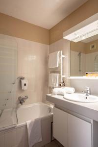 沙勒罗瓦机场公园酒店的浴室配有盥洗盆、浴缸和盥洗盆