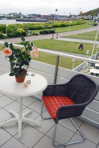 黑尔戈兰岛汉斯特酒店的阳台配有桌子和椅子,提供桌子和鲜花