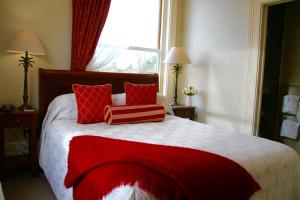 基督城梅尔瓦拉庄园酒店的一间卧室配有一张带红色枕头的床和一扇窗户