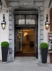 卢尔德The Originals City, Hôtel Astoria Vatican, Lourdes (Inter-Hotel)的两株盆栽植物的建筑物入口