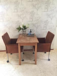 埃曼B&B De Koraal的一张木桌和两把带鲜花的椅子