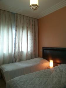 达布阿扎Perle de Tamaris的一间卧室设有两张床、一盏灯和一扇窗户。