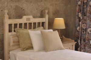贝拉姆卡尔Assos Sunaba Kasri Hotel的一张带白色枕头的床和一张桌子上的台灯