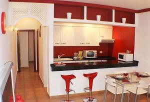 蒂亚斯Apartamentos JANESKA的厨房配有红色和白色的橱柜和桌子